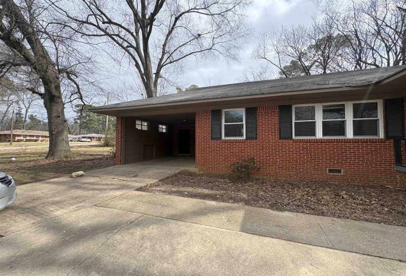 View of property exterior with brick siding, an attached carport, concrete driveway, crawl space, and a shingled roof