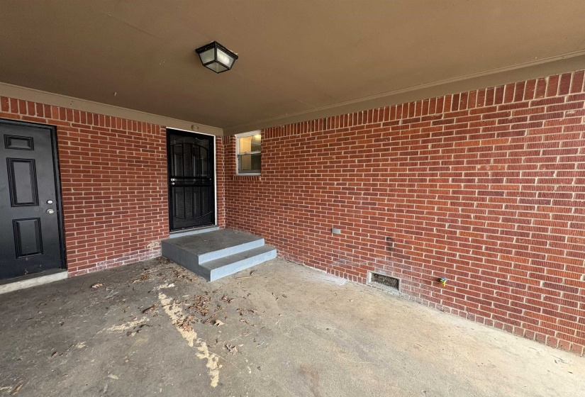 Doorway to property featuring brick siding and a patio area