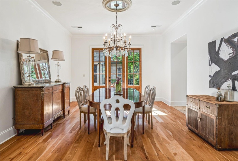 Formal dining space featuring a crystal chandelier, wood-finish flooring, and French doors