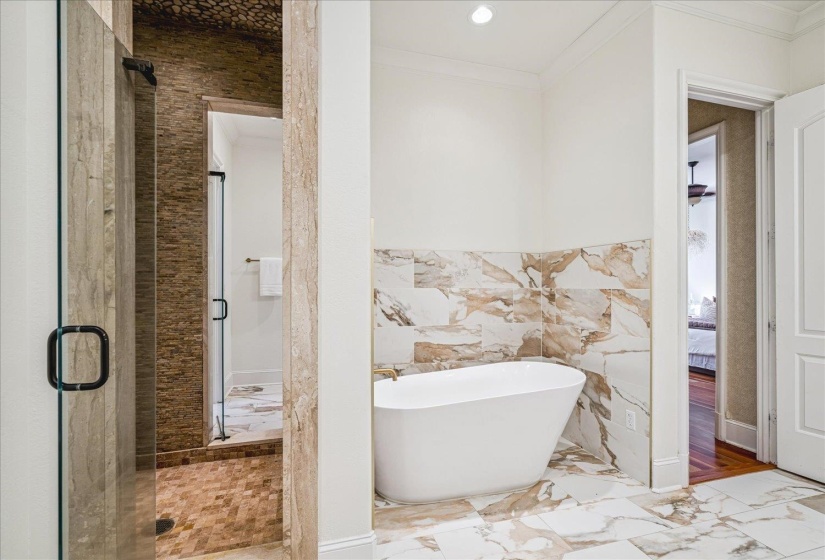 Spacious bathroom featuring a frameless glass shower enclosure, a freestanding soaking tub, and decorative tile accents