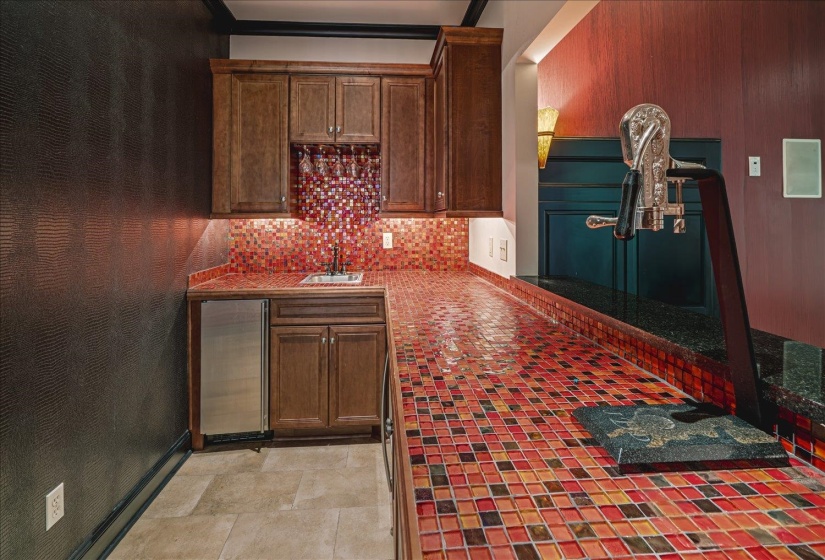 Wet bar featuring mosaic tile countertops and backsplash, wood cabinetry, a built-in beverage refrigerator, and an integrated sink with a faucet