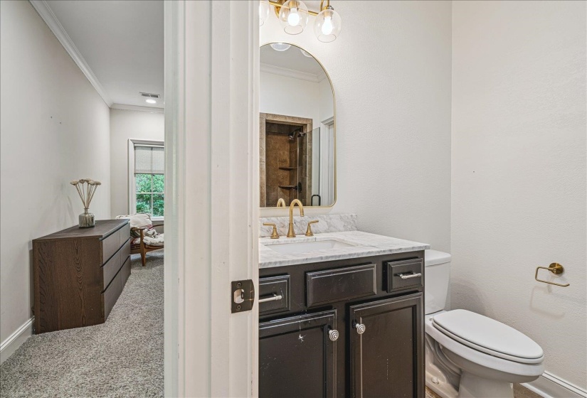 Bathroom vanity featuring a dark wood-finish cabinet with a white countertop and gold-tone hardware