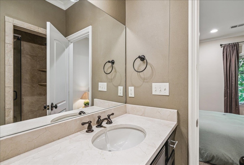 White vanity with an integrated basin, stone countertop, bronze-finish faucet, and a large wall-mounted mirror