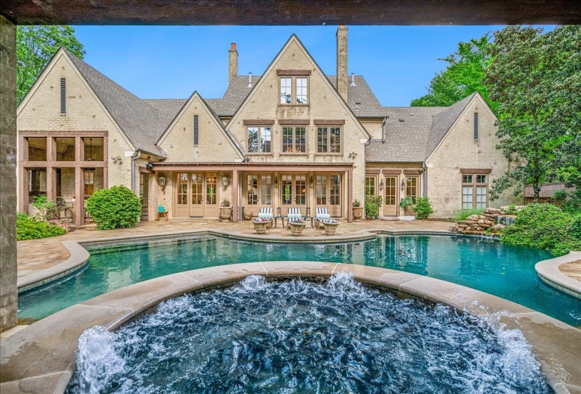 Expansive swimming pool with integrated spa and stone surround