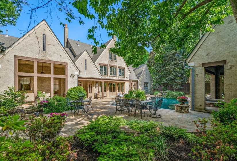 Stone patio with integrated swimming pool, surrounded by mature trees and established landscaping