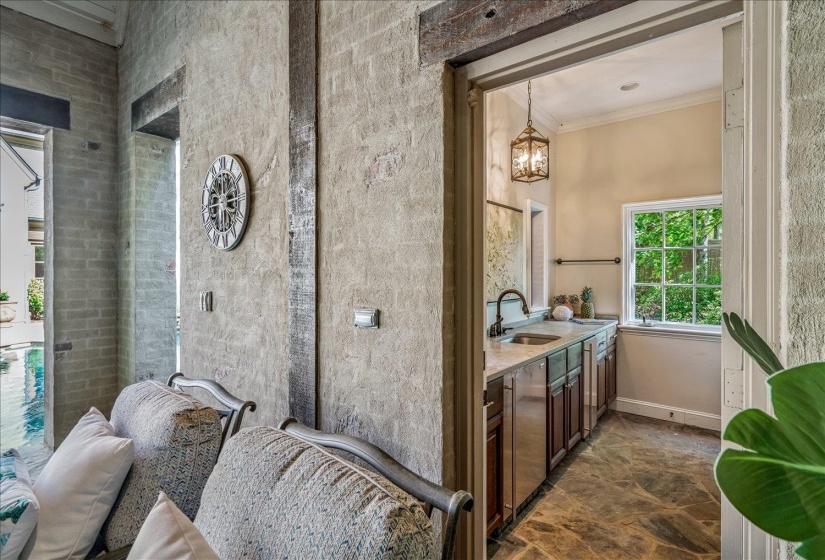 Interior wet bar featuring a single basin sink, dark wood cabinetry, light countertop, and an ornate pendant light fixture