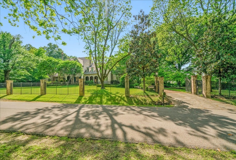 Gated entry featuring stone pillars and wrought iron fencing