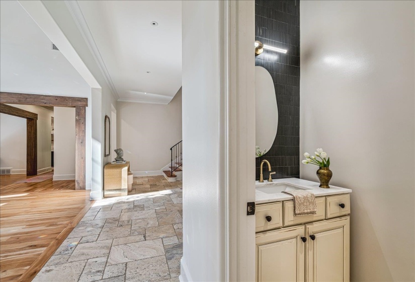 Powder room featuring a vanity with a surface-mount sink, gold-tone faucet, and a contemporary mirror over a dark tile accent wall