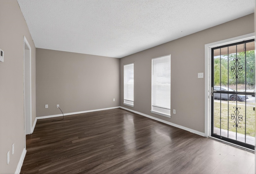 Empty room featuring a textured ceiling, plenty of natural light, and dark wood-style flooring