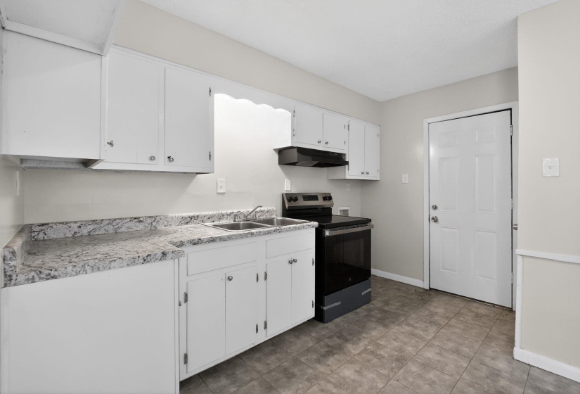 Kitchen with stainless steel electric range oven, white cabinets, and light countertops