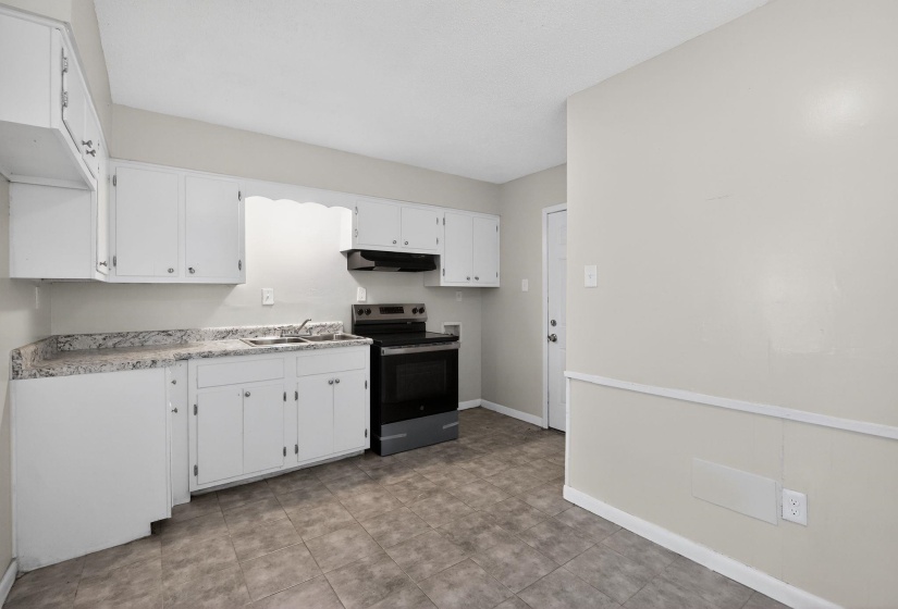 Kitchen with stainless steel range with electric stovetop, white cabinets, and light countertops