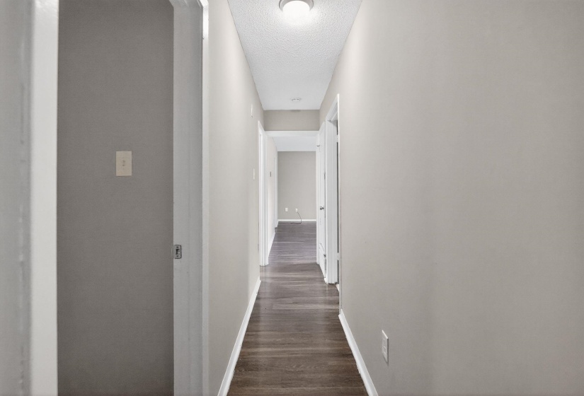 Corridor featuring a textured ceiling and dark wood-style flooring