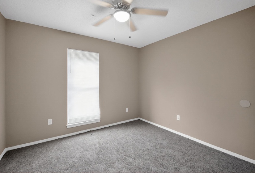 Carpeted empty room featuring ceiling fan and baseboards