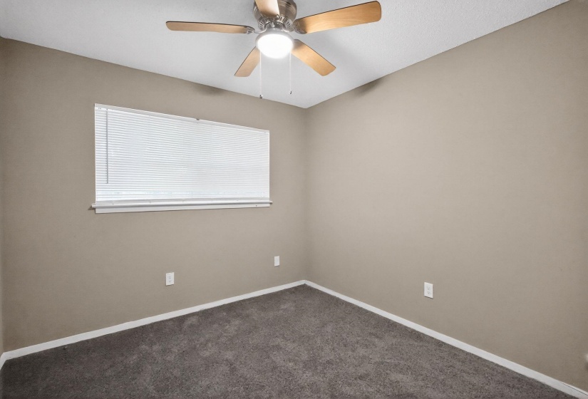 Unfurnished room with a ceiling fan and dark carpet