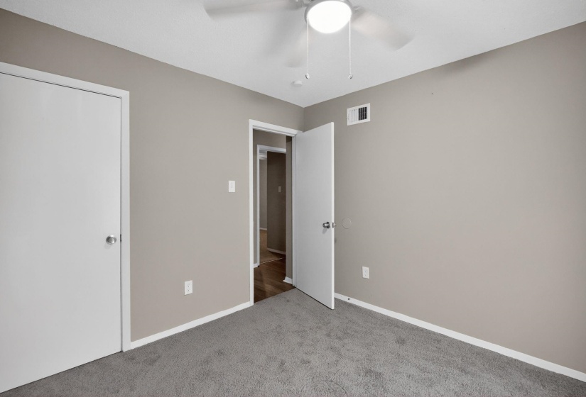 Unfurnished bedroom with light colored carpet and a ceiling fan