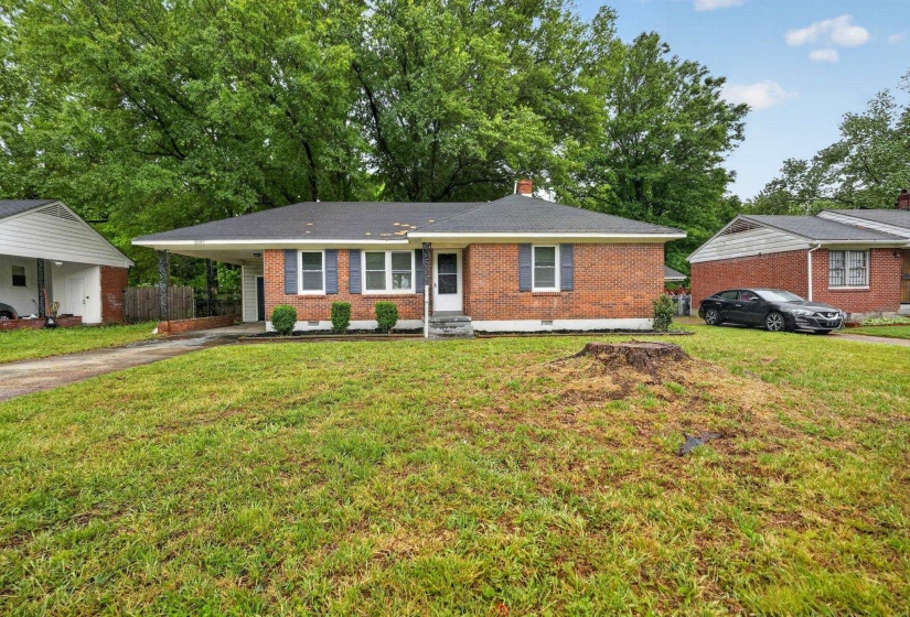 Ranch-style house featuring a carport, a front lawn, brick siding, and concrete driveway