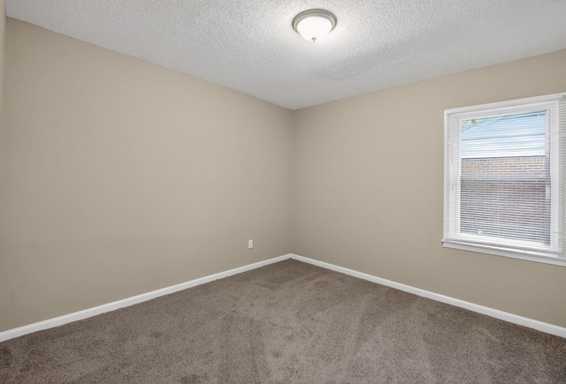 Carpeted empty room featuring baseboards and a textured ceiling
