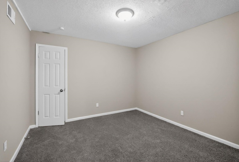 Unfurnished room with dark colored carpet and a textured ceiling