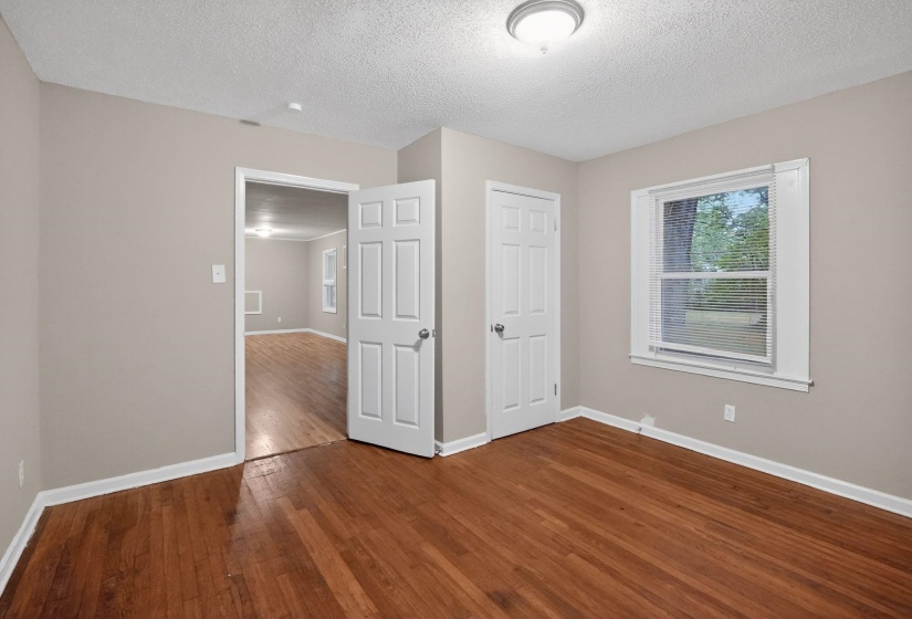 Unfurnished bedroom with dark wood finished floors and a textured ceiling