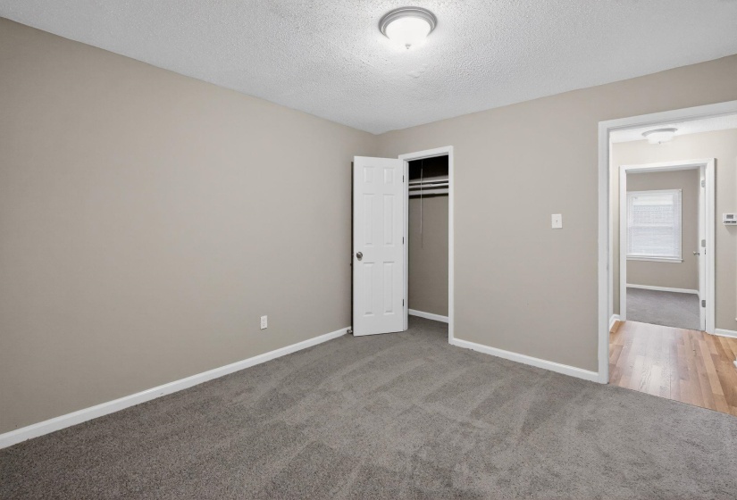 Unfurnished bedroom with light carpet, a closet, and a textured ceiling