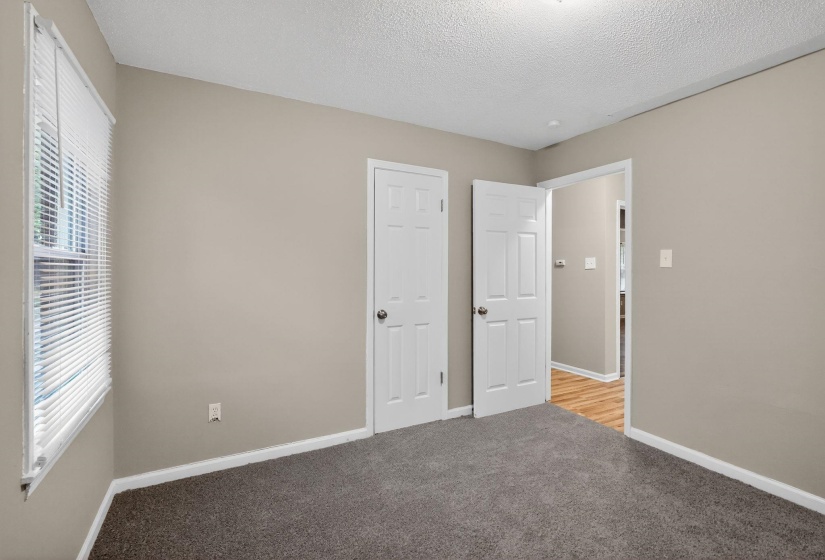 Unfurnished bedroom with light colored carpet and a textured ceiling