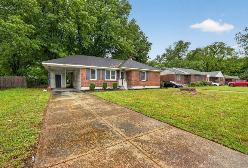 Single story home featuring concrete driveway, a carport, brick siding, and a chimney
