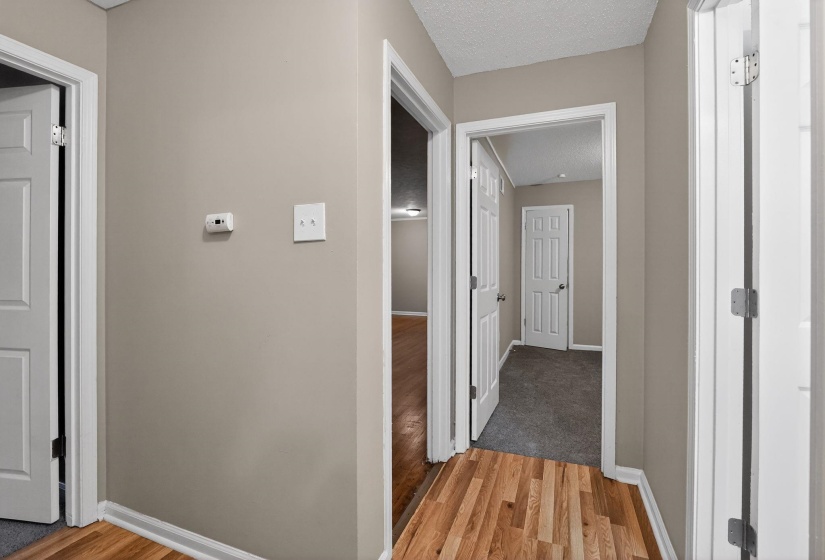 Hallway with light wood finished floors and a textured ceiling