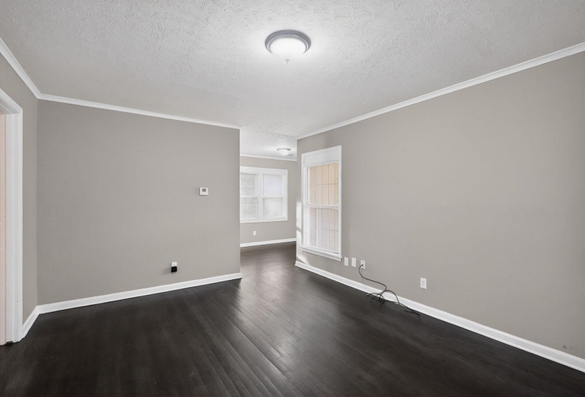 Spacious room with dark wood-finish flooring, light gray wall paint, white trim, and a recessed window