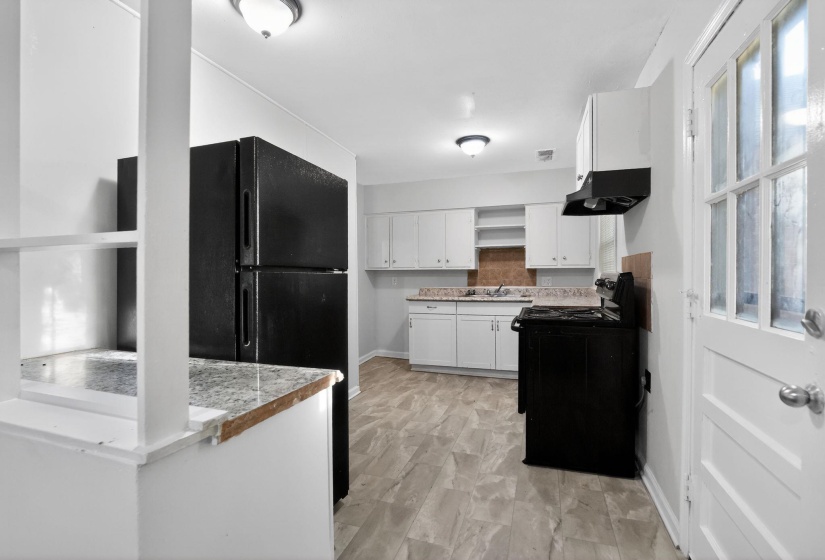 Kitchen featuring white cabinetry, a built-in range hood, a full-size refrigerator, and wood-finish flooring