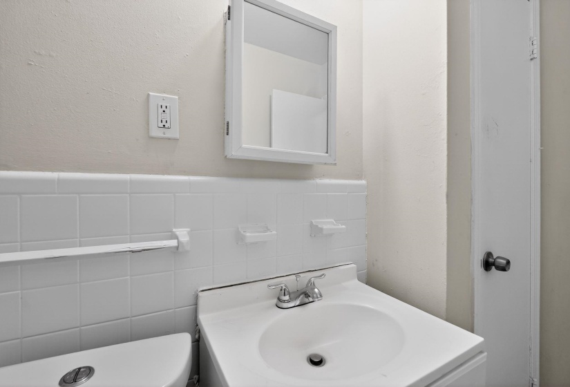 Bathroom vanity with an integrated sink, dual-handle chrome faucet, and mirrored medicine cabinet