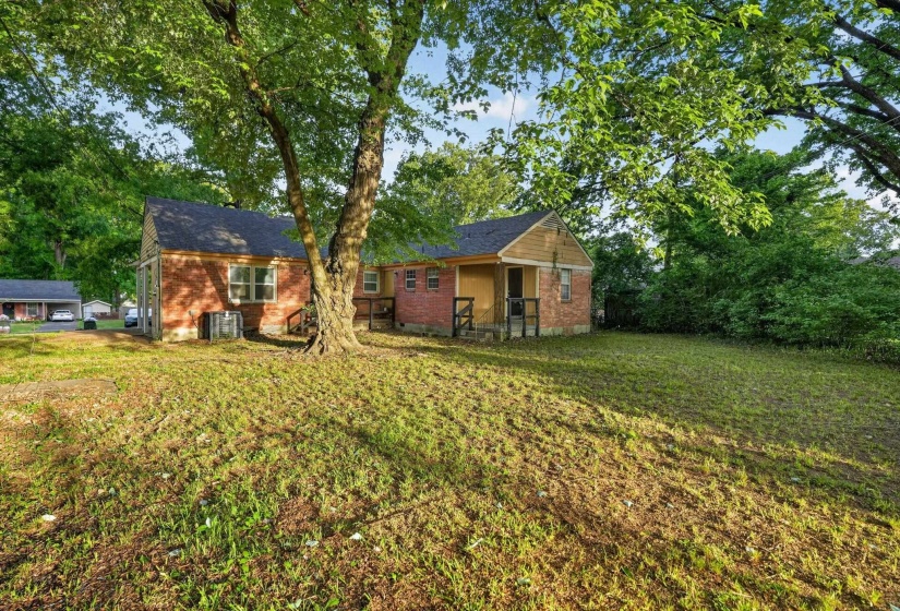 Expansive grassy yard with mature trees providing shade