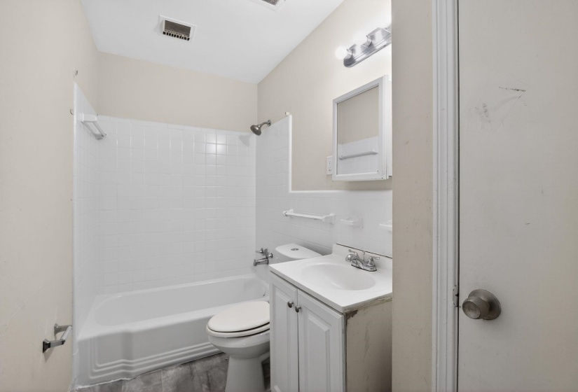 Bathroom featuring a white bathtub, subway tile surround, white vanity with integrated sink, chrome fixtures, and a mirrored medicine cabinet