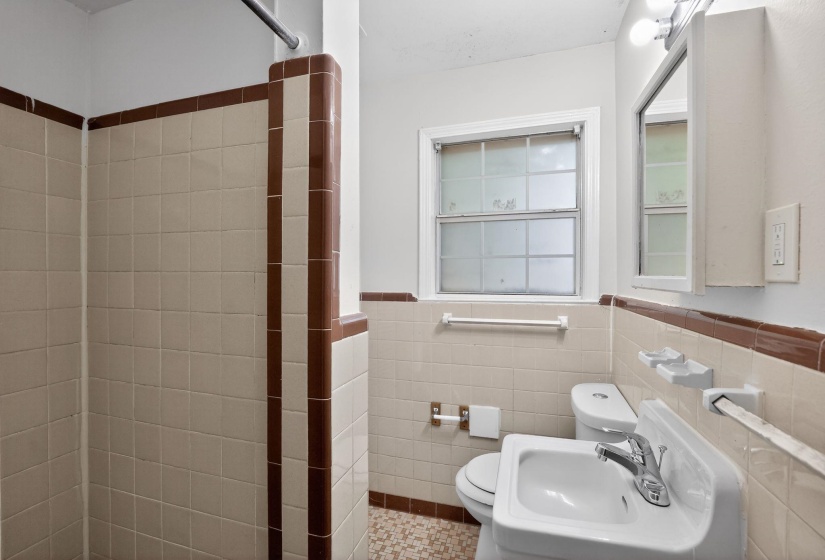 Bathroom with light-colored wall tiles featuring brown accent trim