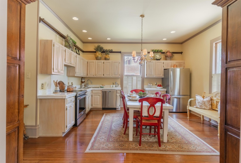 Kitchen featuring appliances with stainless steel finishes, hardwood / wood-style flooring, an inviting chandelier, and ornamental molding