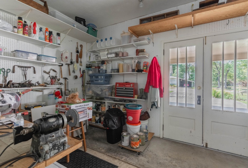 Garage featuring a workshop area. Doors from the carport