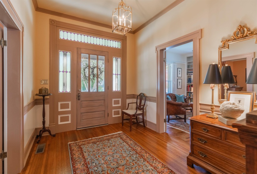 Entryway featuring ornamental molding, hardwood flooring, and an inviting chandelier