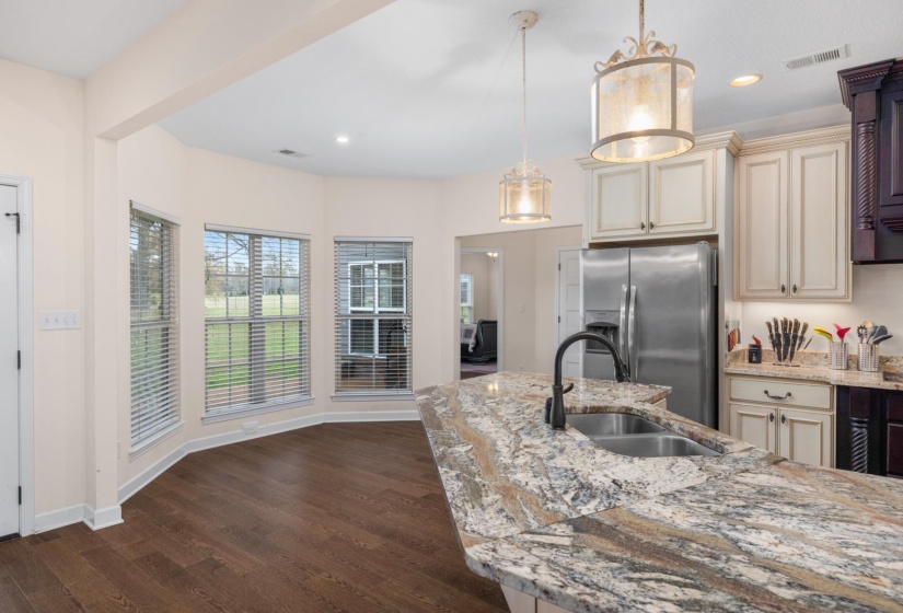 Kitchen featuring an expansive island with a double basin sink, stone countertops, and a gooseneck faucet