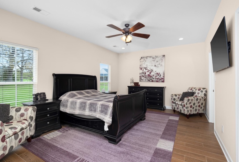 Spacious room featuring wood-finish flooring, light-toned walls, and a ceiling fan with integrated lighting
