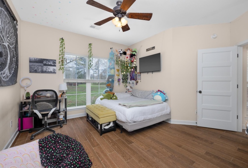 Interior room featuring wood-finish flooring, a ceiling fan with integrated lighting, and multiple windows with blinds
