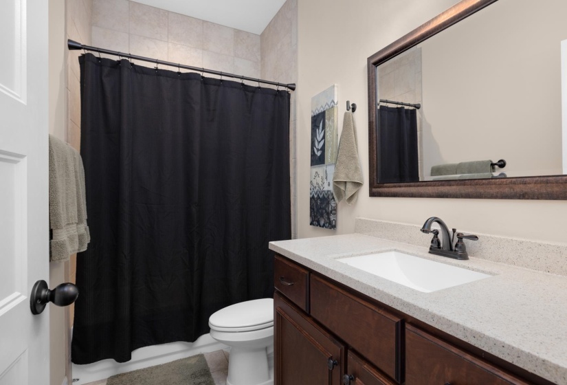 Bathroom vanity with a white rectangular undermount sink, a dark bronze faucet, and a light speckled countertop