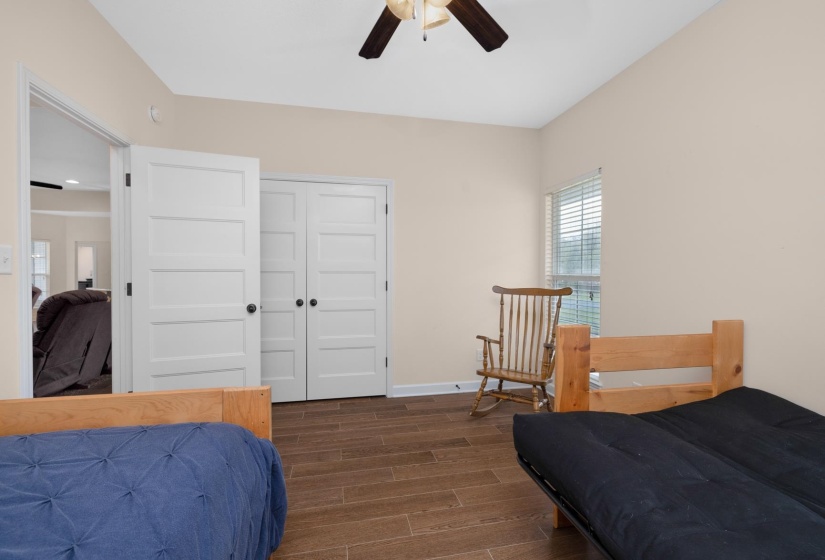 Interior room featuring wood-finish flooring, a ceiling fan, and a window with horizontal blinds