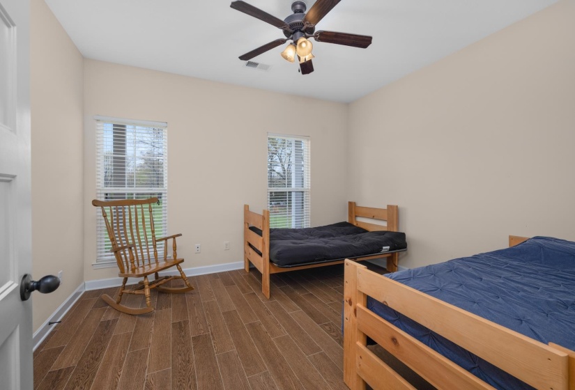Interior room featuring light beige walls, wood-finish flooring, and a ceiling fan with integrated lighting