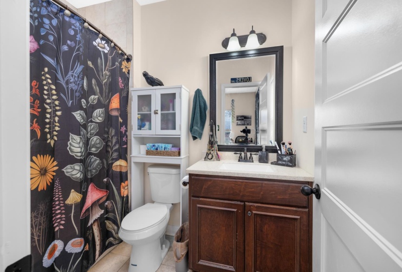 Bathroom featuring a wood-finish vanity with a light-colored countertop, an overhead lighting fixture, and a framed mirror