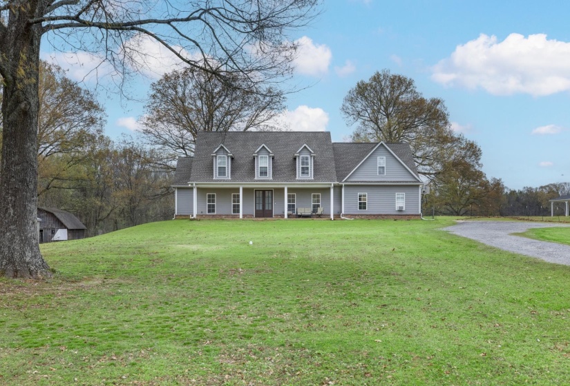 Traditional-style home featuring light gray siding and a dormered roofline