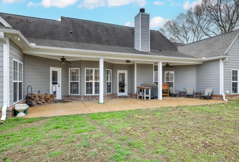Expansive concrete patio with a covered porch featuring multiple access points to the interior