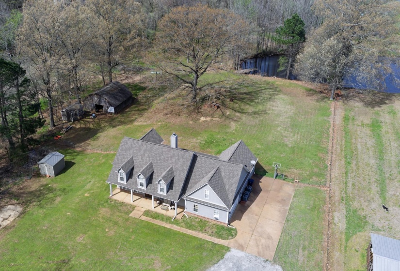 Expansive property featuring a gray-sided residence with multiple dormers, a covered front porch, and an attached concrete driveway