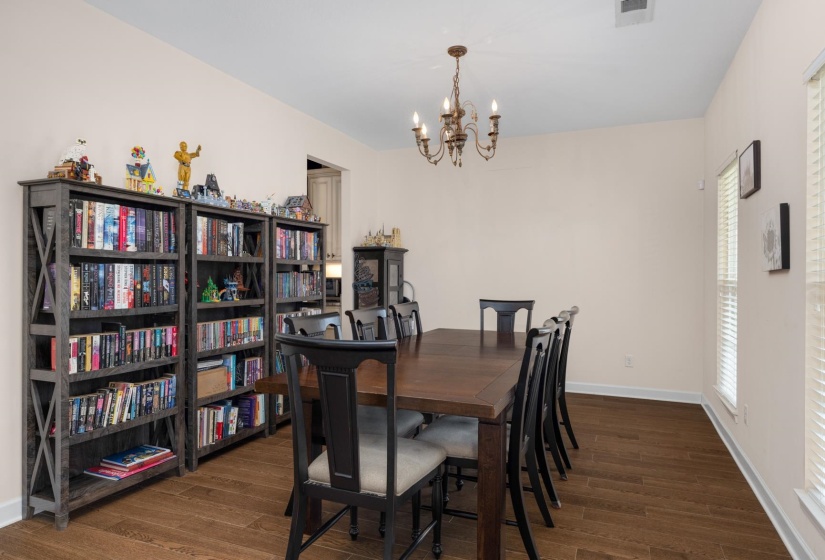 Dining area featuring wood-finish flooring, a traditional chandelier, multiple windows with blinds, and light-toned wall finishes