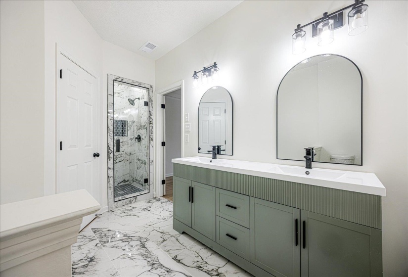Double vanity featuring a sage green cabinet with reeded accents, two integrated sinks, and matte black fixtures