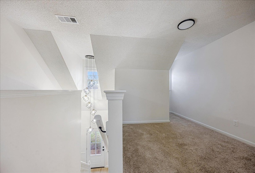 Upper level landing featuring light brown carpet and a contemporary multi-bulb chandelier