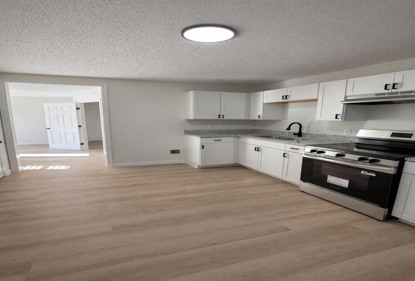 Kitchen featuring wood-finish flooring, white cabinetry, a stainless steel range, and a black gooseneck faucet